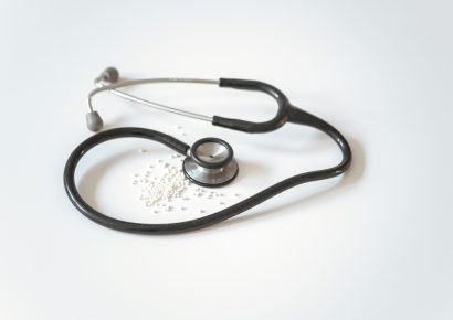 A black and metal silver stethoscope is folding on a white table.