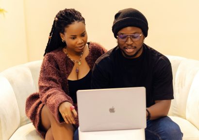 Two people sit on a couch looking at a laptop