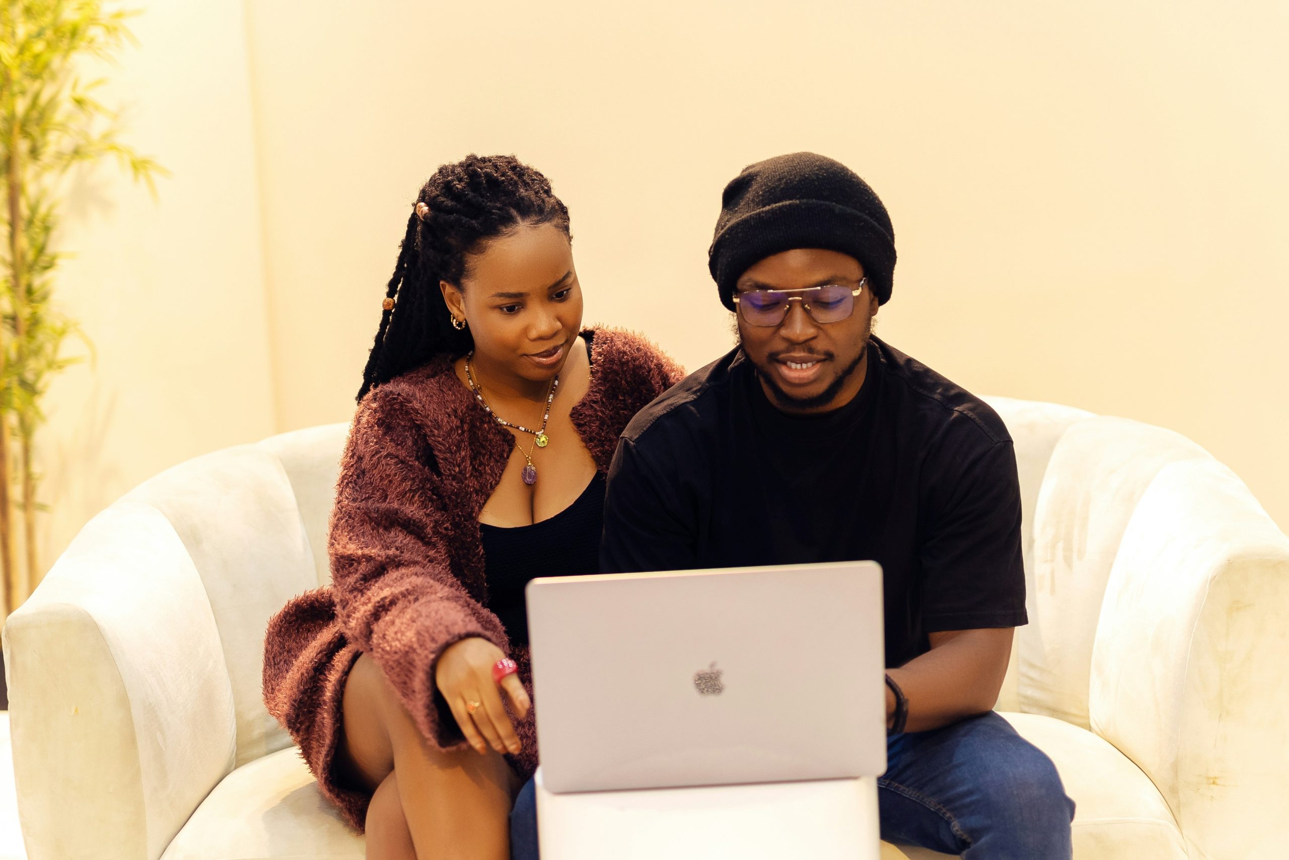 Two people sit on a couch looking at a laptop